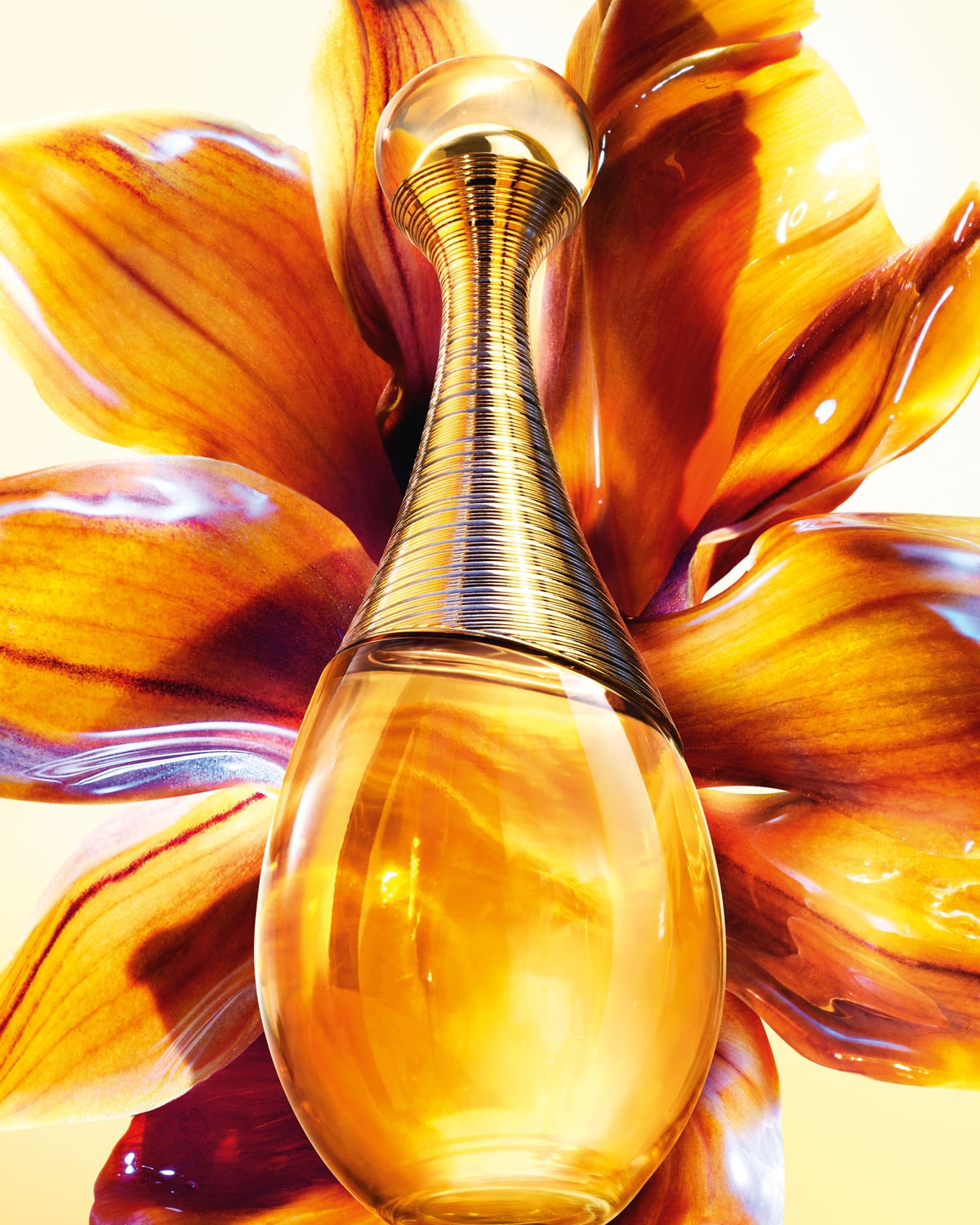 Arany színű parfümös üveg virágszirmok előtt, elegáns és kifinomult illatot sugallva.