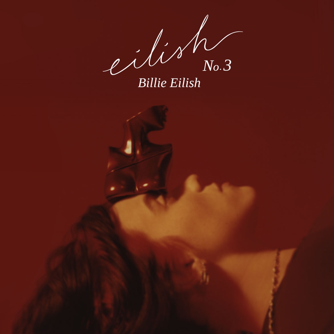 Billie Eilish Eilish No. 3 parfümje vörös háttér előtt, a parfümös üveg egy női alakot formáz, aki az arcán egyensúlyoz.