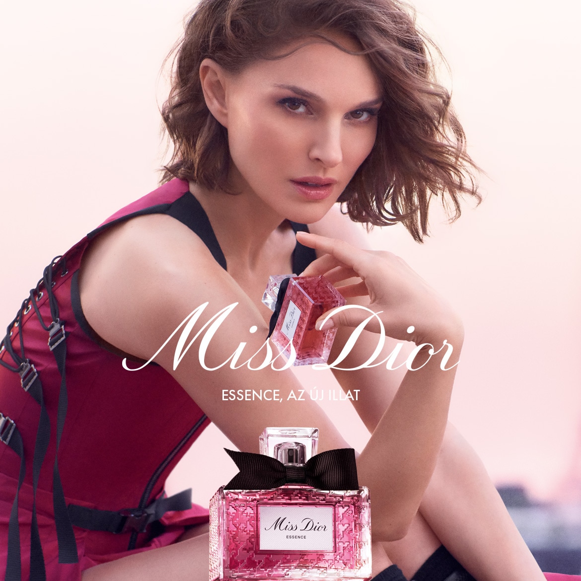 Natalie Portman a Miss Dior Essence reklámkampányában, kezében a rózsaszín, kockás üvegcsés parfümmel, melyet fekete masni díszít.