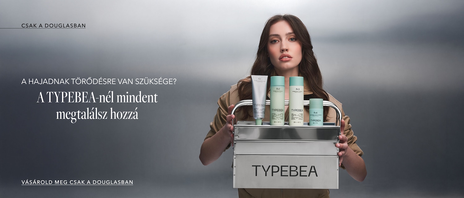 A TYPEBEA termékek ezüst színű tartóban sorakoznak, melyet egy nő tart, a termékek között megtalálható R-1 hajpakolás, R-2 sampon, R-3 hajbalzsam és R-4 hajápoló, vásárold meg a Douglasban!