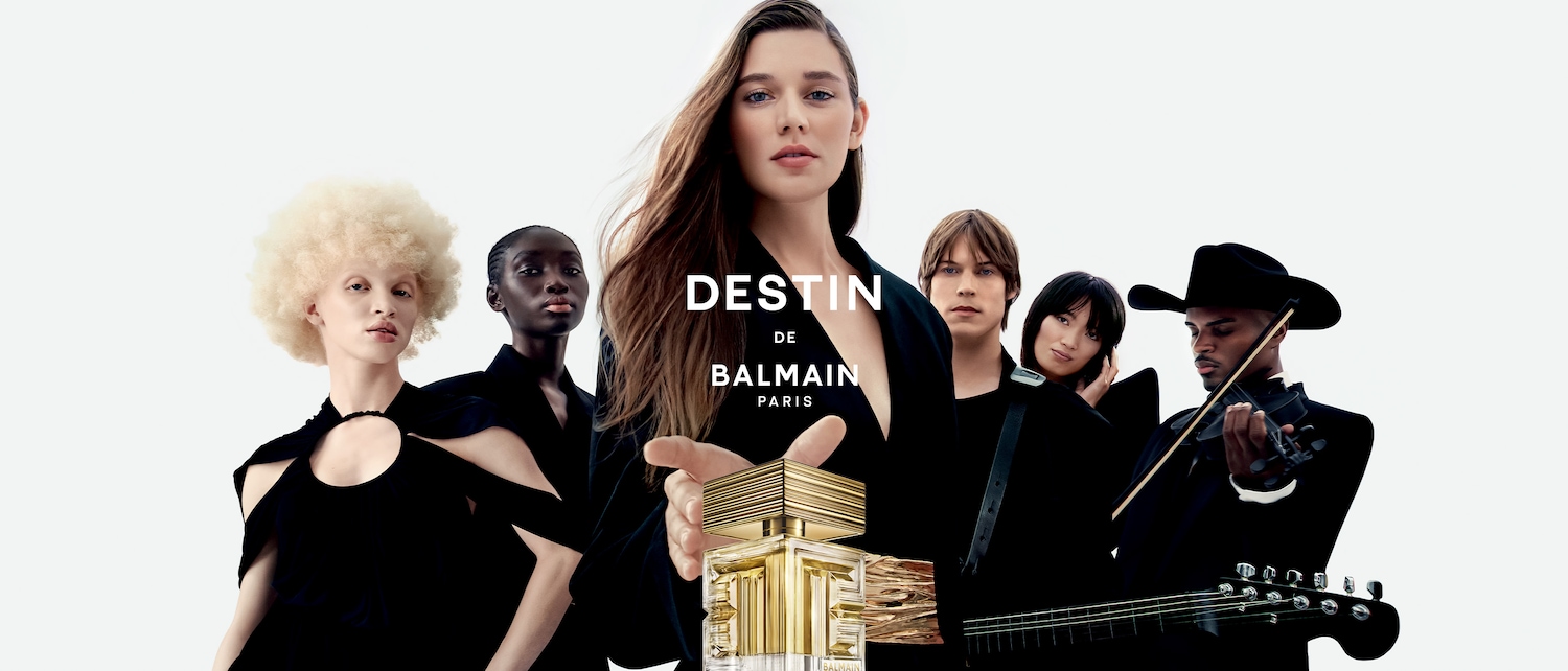 A Destin de Balmain Paris illatcsalád kampányképe, melyen különböző bőrszínű modellek láthatóak, köztük egy nő, aki a Destin de Balmain üvegét tartja.